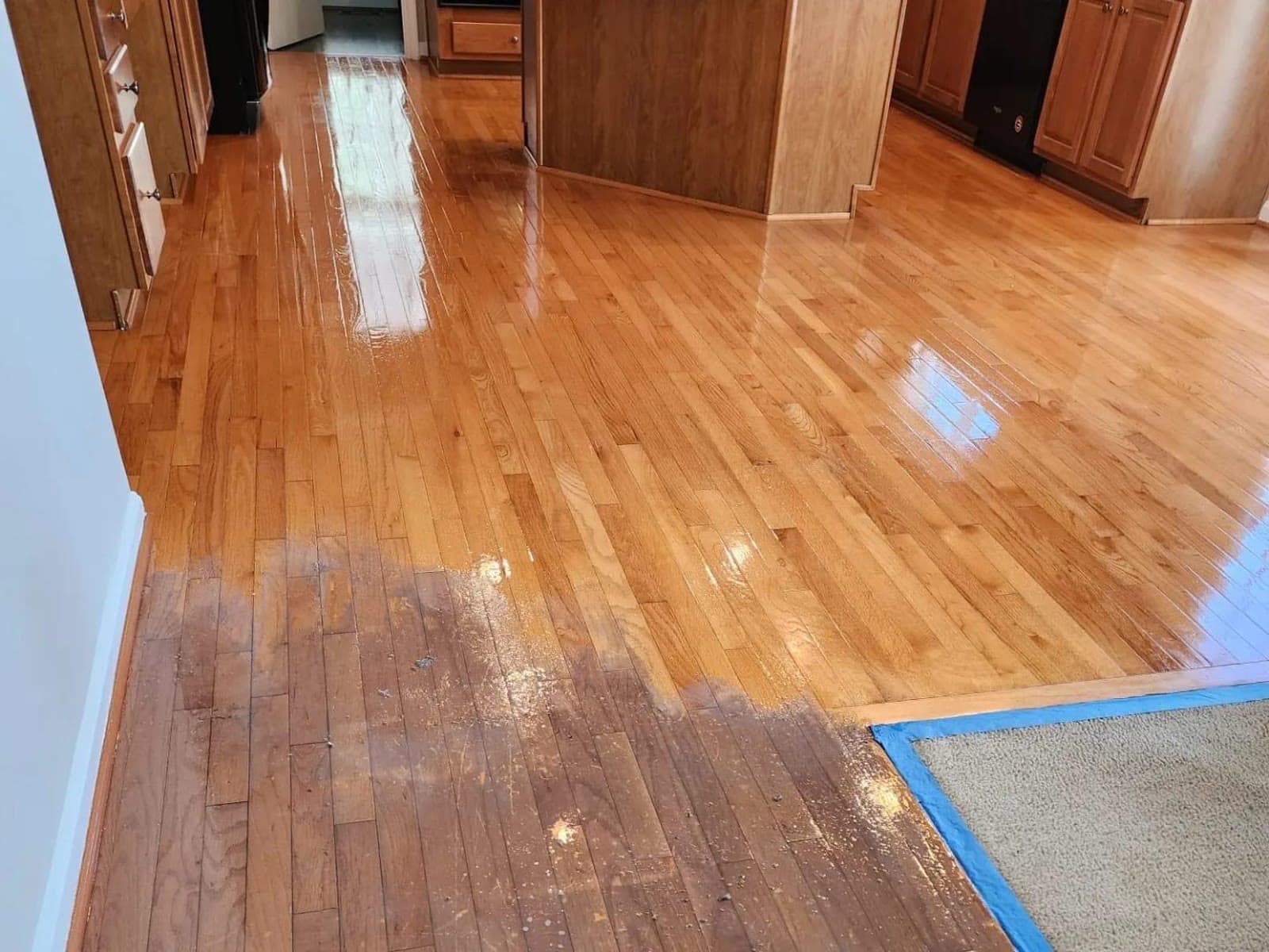 Hardwood floor mid-restoration, worn finish next to a freshly buffed, glossy section