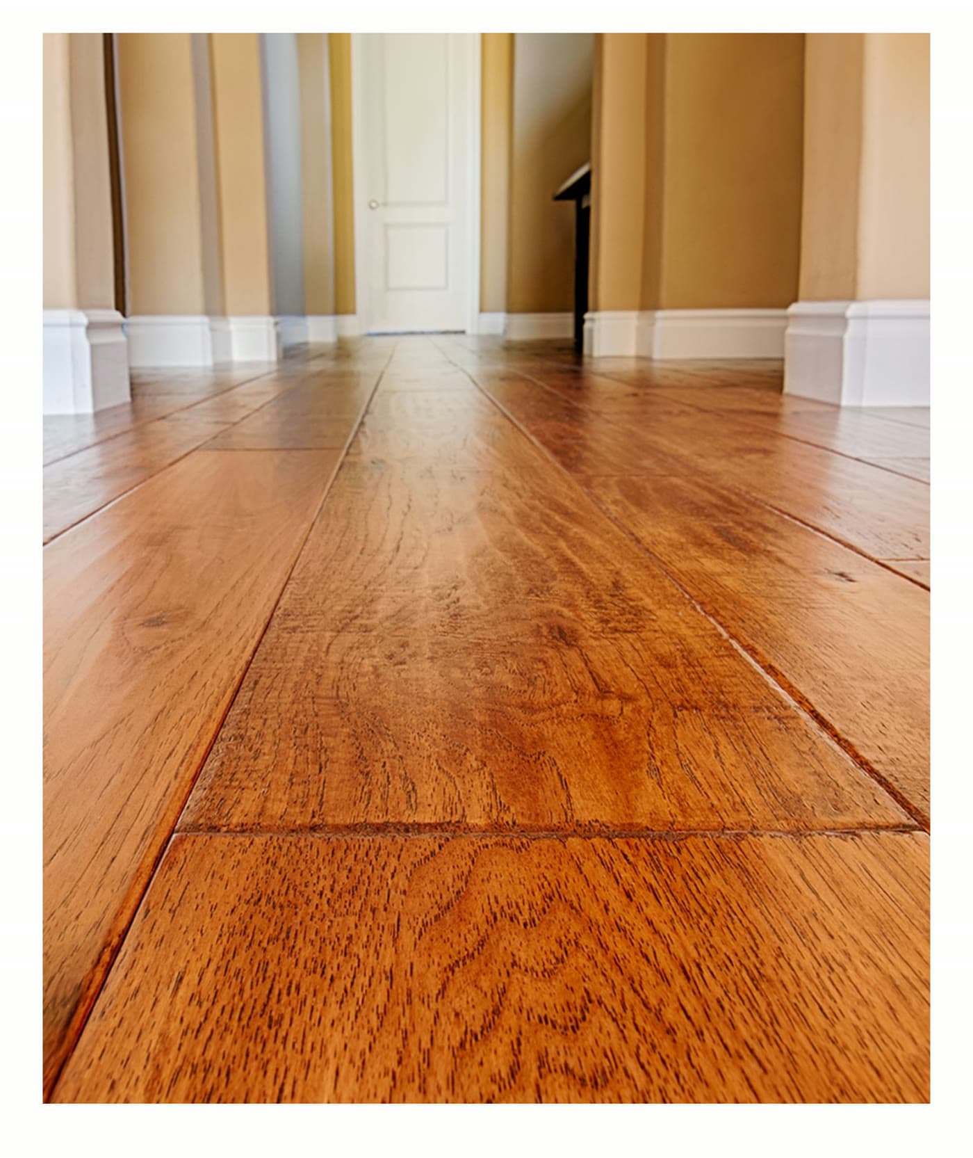Restored hardwood hallway floor leading to a bright doorway